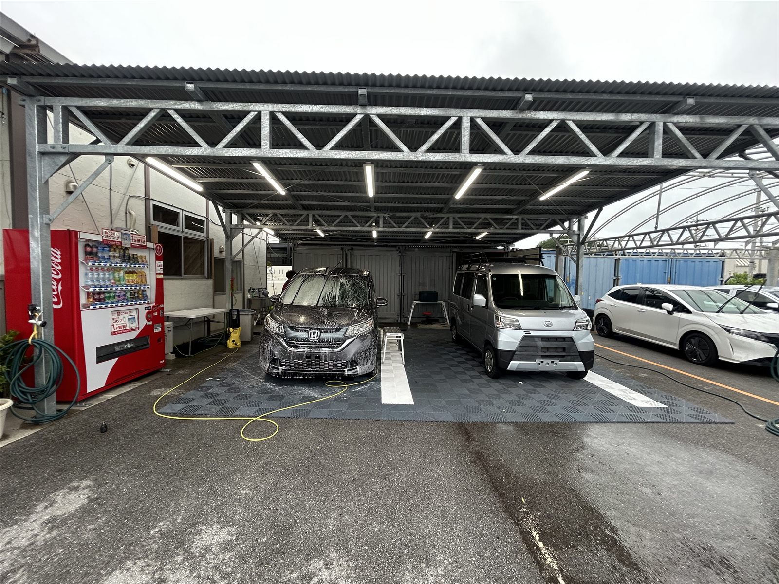 店の屋根の下に並んだ代車のミニバンと軽バン